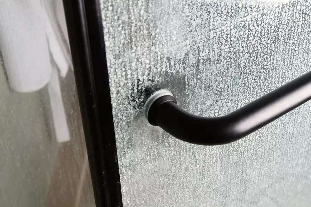 Vidro do box tomado por calcário incrustado
